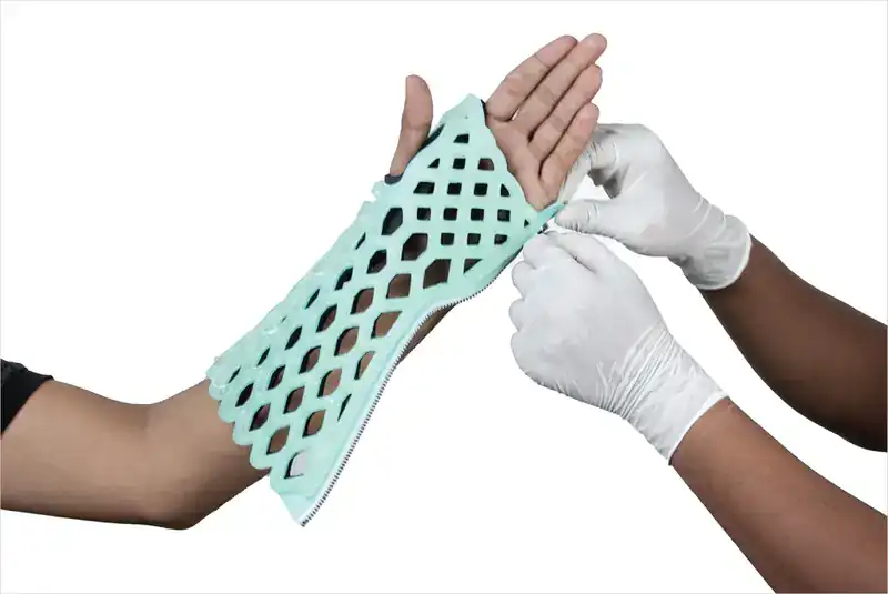 Gloved hands zipping a FlexiOH immobilizer closed on a forearm